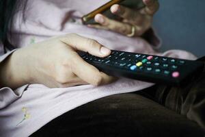 primer plano de la mano de las mujeres sosteniendo el control remoto de la televisión. foto