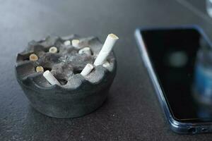 Close up burning cigarette in ashtray on table photo