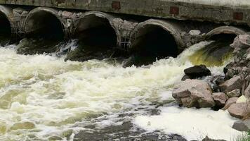 ambientale inquinamento, ambientale disastro. scarico di inquinata liquame in il fiume a partire dal fabbrica calcestruzzo tubi. pericoloso rifiuto acqua. ambientale protezione. acqua inquinamento. video