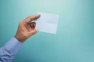 hand of man holding blue color paper card . photo