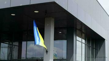 il nazionale bandiera di Ucraina svolazza nel il vento su un' pennone, su un' costruzione. blu e giallo colori su il ucraino bandiera. bandiera di Ucraina su il facciata di il governo costruzione. video