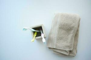 colorful toothbrushes in white mug and towel on white background photo