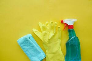 plastic spray bottle, gloves and towel on yellow table photo