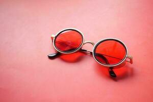 a red Round sunglasses on red background photo