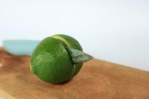 Green limes sliced on a cutting board on a white background photo