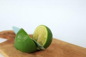 verde limas rebanado en un corte tablero en un blanco antecedentes foto