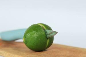 Green limes sliced on a cutting board on a white background photo