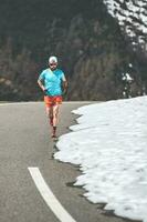 masculino corredor cuesta arriba en alpino pasar la carretera foto