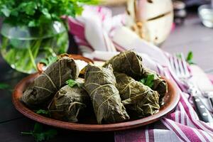 Dolma. Stuffed grape leaves with rice and meat on dark table. Middle eastern cuisine. photo