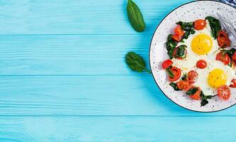 Breakfast. Ketogenic diet food. Fried egg, spinach, and tomatoes. Keto, paleo breakfast. Top view, copy space photo