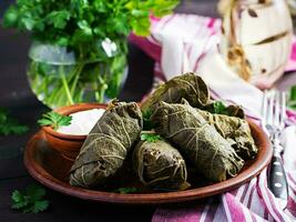 Dolma. Stuffed grape leaves with rice and meat on dark table. Middle eastern cuisine. photo