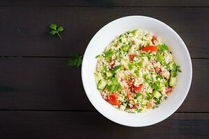 Traditional Lebanese Salad Tabbouleh. Couscous with parsley, tomato, cucumber, lemon and olive oil. Middle Eastern cuisine. Top view, copy space photo