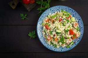 Traditional Lebanese Salad Tabbouleh. Couscous with parsley, tomato, cucumber, lemon and olive oil. Middle Eastern cuisine. Top view, copy space photo