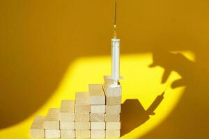 shadow of a man's hand about to steal a syringe with a vaccine on yellow background photo