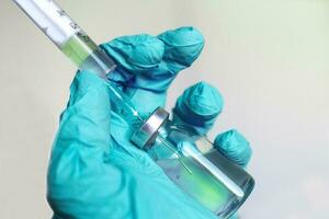 Vial filled with liquid vaccine in medical lab with syringe.doctor's hand holds ampoule and syringe photo