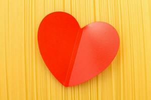 spaghetti yellow background with a red heart close. raw pasta macro photo