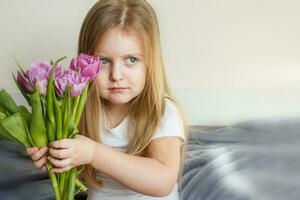 portrait of litlle girl with bouquet of flowers tulips in her hands photo