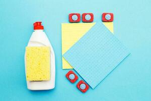 capsules for dishwashers, dishwashing detergents liquid, kitchen rag and sponges on a blue background. photo