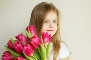 retrato de niña pequeña con ramo de flores tulipanes en sus manos foto