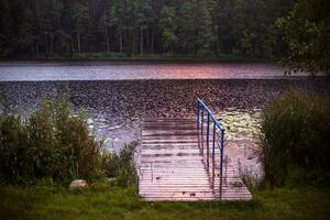 landscape lake rural wooden pier on the shore on a rainy day photo