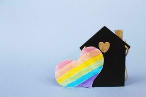 heart in the form of a lgbt flag next to a miniature toy house. photo