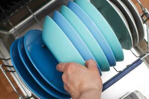 hand of a woman open dishwasher with clean dishes in the kitchen photo