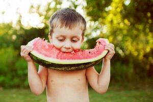 happy smiling child boy eating the watermelon outdoor in the backyard photo