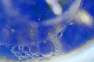 las burbujas de aceite se cierran. círculos de agua macro. fondo azul claro abstracto foto