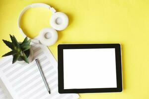 Top view open music book, headphones and a pen on a yellow background. mock up for music lessons photo