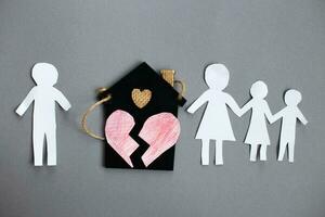 Paper chain cut family near toy house on gray background. Divorce and broken family concept photo