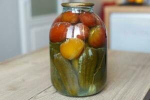 spoiled can of vegetable seaming. Glass jar with homemade pickled tomatos and cucumbers with white fungus photo