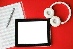 Top view open music book, headphones and a pen on a red background. mock up for music lessons photo