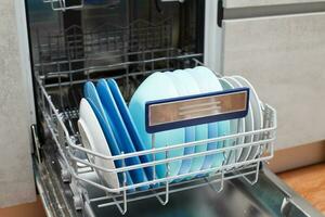 Open dishwasher with clean dishes in the kitchen photo