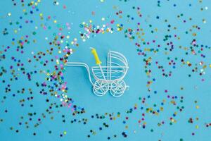 One year birthday.baby stroller with candle in form of the number one on a blue background with stars confetti sequins photo