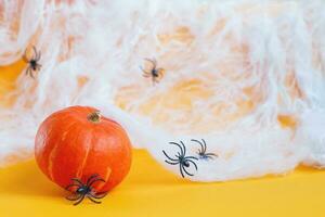 calabaza de Halloween con tela de araña y arañas negras sobre fondo naranja. foto