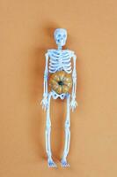 esqueleto con calabaza sobre fondo naranja. concepto de halloween foto