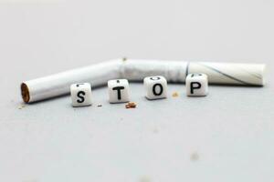 broken cigarette with the word stop on gray background close. stop smoking concept photo