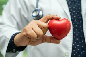 Doctor holding a red heart in hospital ward, healthy strong medical concept. photo