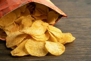 Potato chips, delicious BBQ seasoning spicy for crips, thin slice deep fried snack fast food in open bag. photo