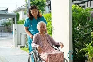 Caregiver help and care Asian senior woman patient sitting on wheelchair to ramp in hospital, healthy strong medical concept. photo