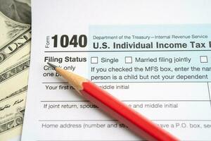 formulario de declaración de impuestos 1040 con bandera estadounidense y billete en dólares, ingreso individual estadounidense. foto