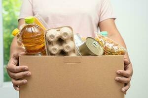 voluntarios poniendo varios alimentos secos en cajas de donación para ayudar a las personas. foto