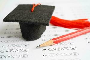 Graduation gap hat and pencil on answer sheet background, Education study testing learning teach concept. photo