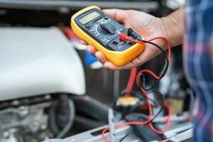 Asian auto mechanic check for repair under the hood of broken down car on the side of the road. photo