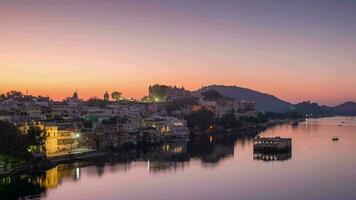 udaipur paisaje urbano a amanecer. el majestuoso ciudad palacio y barcos montando en lago picola, viaje destino en rajastán, India. hora lapso. video