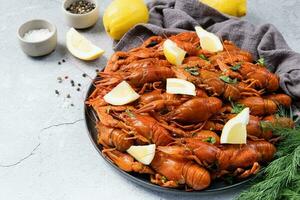 top view of cooked crawfish platter with lemons and spices on cement background photo