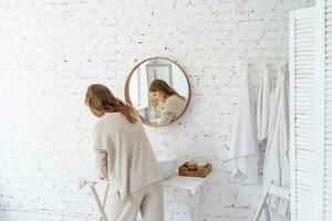 Woman looking at the mirror, making up in the morning photo