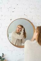 Woman looking at the mirror, making up in the morning photo