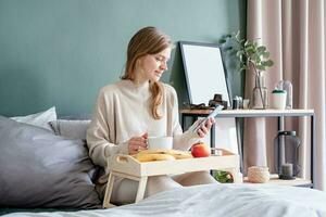 mujer sentado a cama a hogar Bebiendo café foto