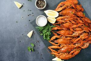 top view of cooked crawfish with lemons and spices on dark cement background photo
